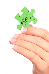 Hand holding drawn light bulb on puzzle